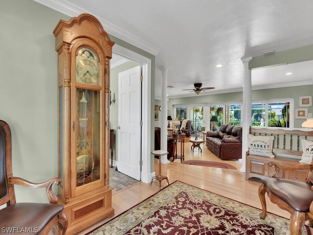 interior space with light wood-type flooring, decorative columns, ceiling fan, and ornamental molding