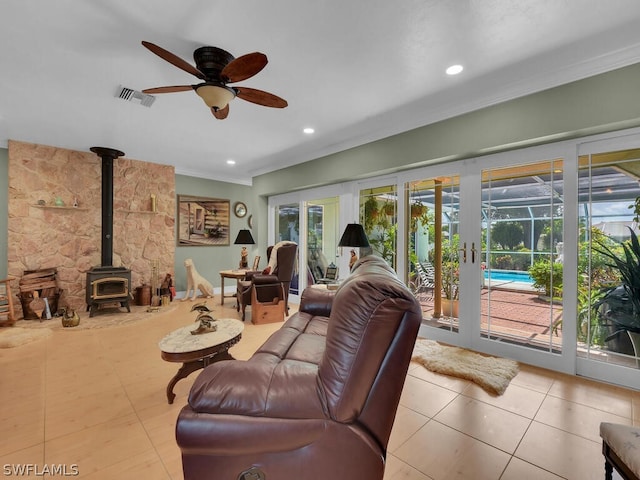 living room featuring a wood stove, ceiling fan, and crown molding