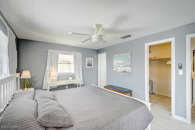 bedroom featuring a spacious closet, a closet, light tile patterned floors, and ceiling fan