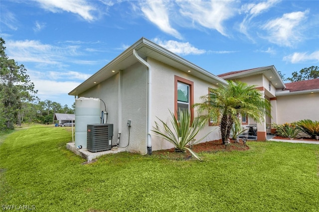 view of side of property with a yard and central air condition unit