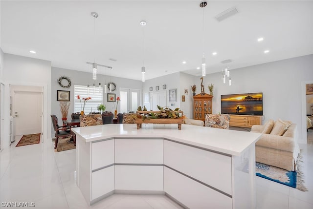 kitchen featuring decorative light fixtures, white cabinets, a kitchen island, and light tile floors