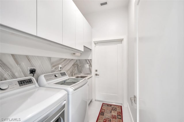 clothes washing area with washing machine and dryer, electric dryer hookup, light tile floors, sink, and cabinets