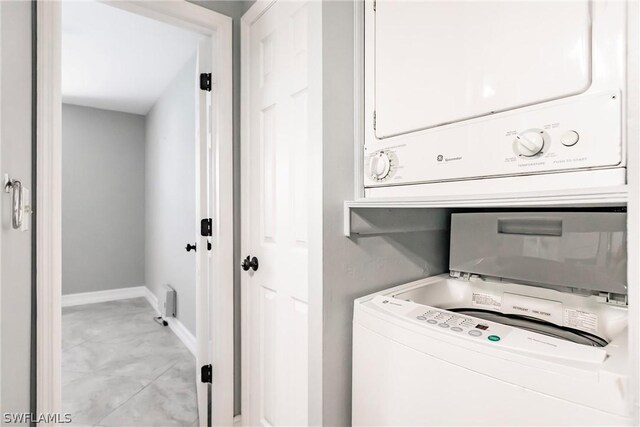 clothes washing area with stacked washing maching and dryer and light tile floors