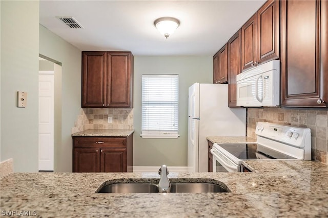 kitchen featuring sink, light stone countertops, white appliances, and tasteful backsplash