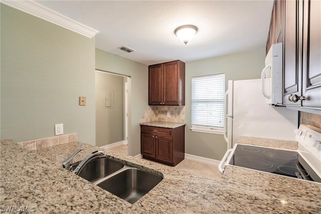 kitchen featuring sink, light stone counters, backsplash, and stove