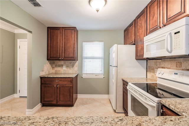 kitchen with backsplash, light stone countertops, white appliances, and light tile floors