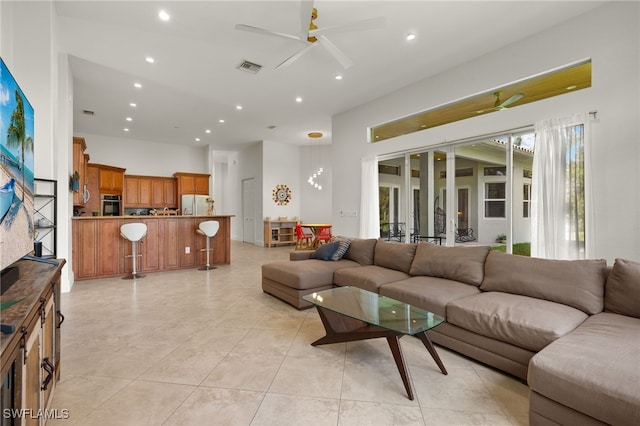 living room featuring ceiling fan, light tile patterned flooring, and a towering ceiling