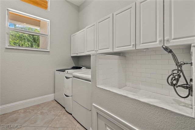 laundry room featuring washer and dryer, cabinets, and light tile patterned flooring