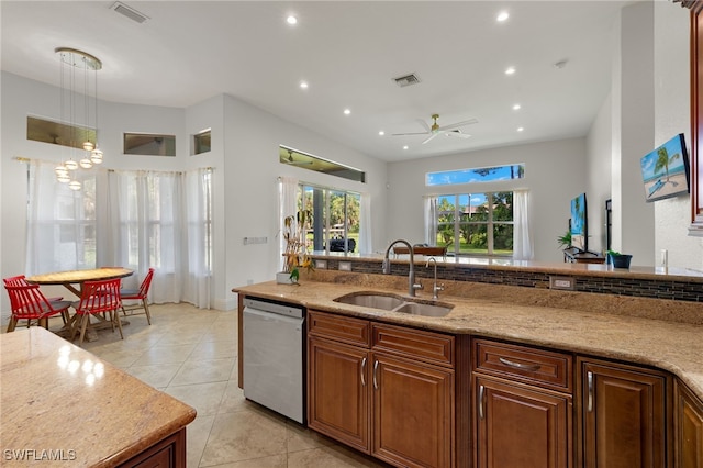 kitchen featuring decorative light fixtures, dishwasher, sink, light tile patterned floors, and light stone counters