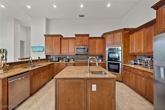 kitchen featuring decorative backsplash, sink, stainless steel appliances, and a center island with sink