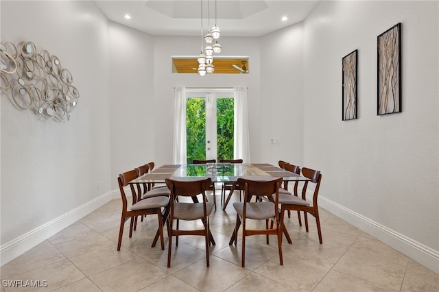 tiled dining area featuring a raised ceiling, french doors, and a towering ceiling