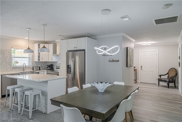 dining area featuring sink, light hardwood / wood-style floors, and ornamental molding