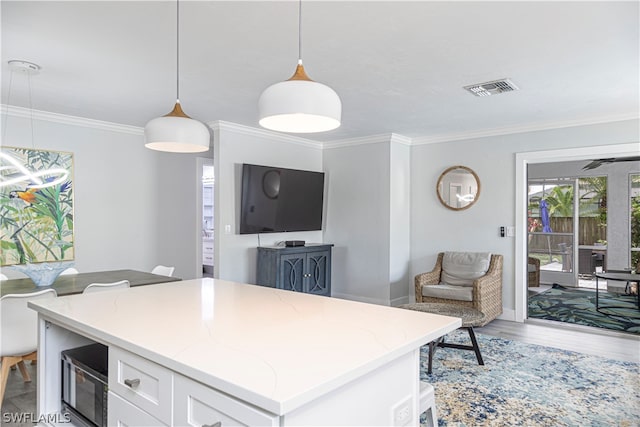 kitchen with crown molding, light stone countertops, white cabinets, hardwood / wood-style flooring, and decorative light fixtures