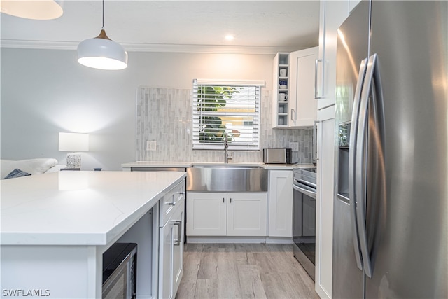 kitchen with white cabinetry, hanging light fixtures, light wood-type flooring, appliances with stainless steel finishes, and backsplash