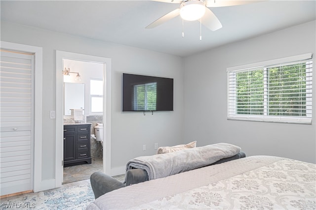 bedroom featuring ceiling fan, ensuite bath, and light tile floors