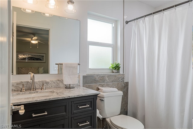 bathroom featuring ceiling fan, vanity, toilet, and tile walls