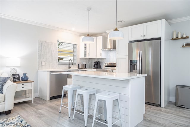 kitchen with light hardwood / wood-style floors, stainless steel appliances, tasteful backsplash, white cabinets, and pendant lighting