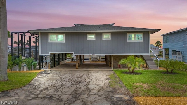 back house at dusk with a carport and a lawn