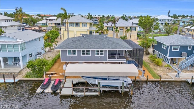 back of house with a residential view, glass enclosure, a water view, and boat lift