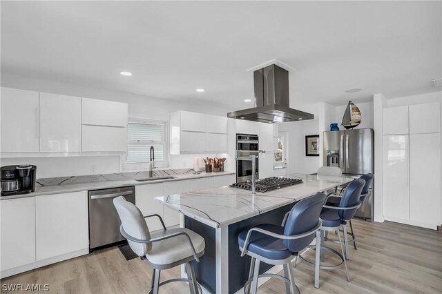 kitchen featuring island range hood, stainless steel appliances, sink, white cabinets, and a center island