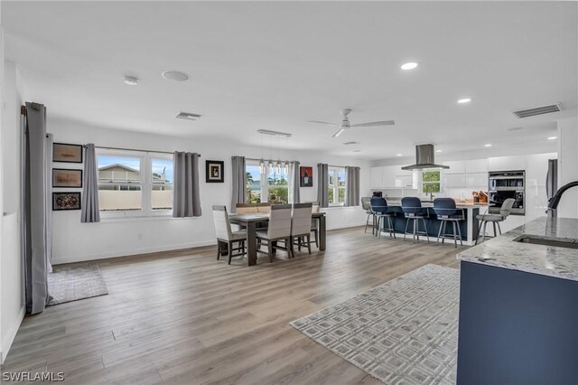 dining area with light hardwood / wood-style flooring, ceiling fan, and sink