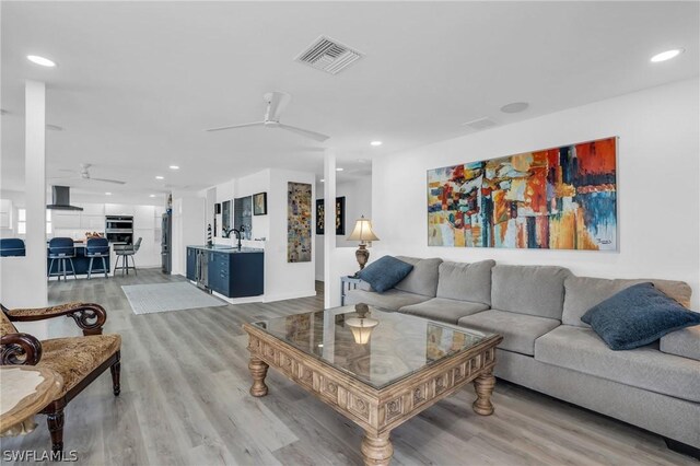 living room with light hardwood / wood-style floors, ceiling fan, and sink