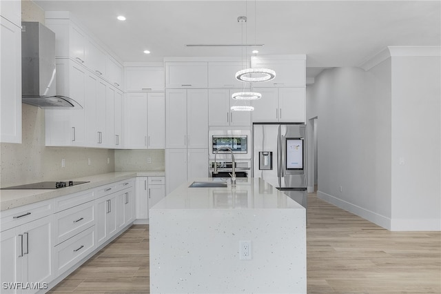 kitchen featuring wall chimney range hood, hanging light fixtures, stainless steel appliances, and light hardwood / wood-style floors