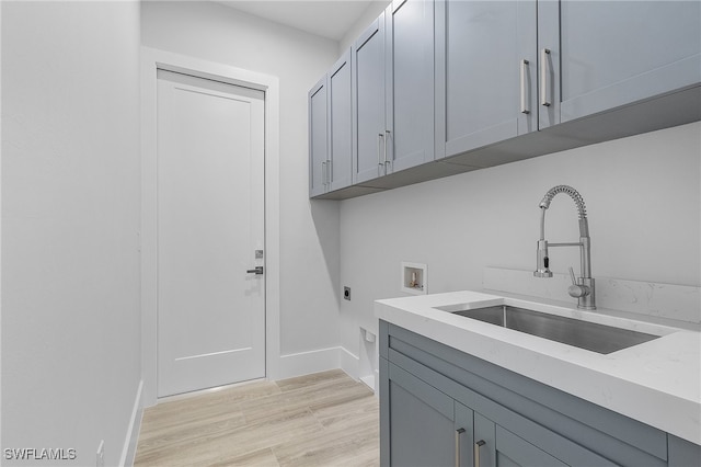 laundry area featuring cabinets, hookup for a washing machine, light hardwood / wood-style flooring, sink, and hookup for an electric dryer