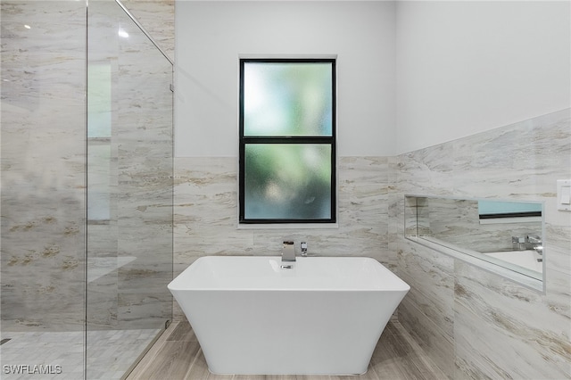 bathroom featuring tile walls and shower with separate bathtub