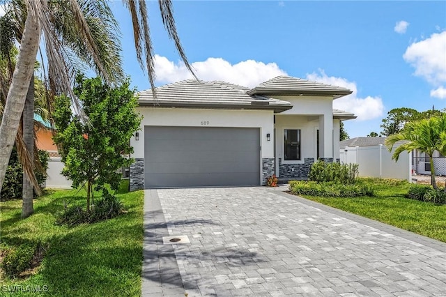 689 101st Ave N, Naples, FL 34108 - prairie-style home featuring stone siding, decorative driveway, an attached garage, stucco siding, and a tile roof