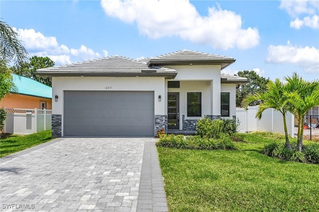 689 101st Ave N, Naples, FL 34108 - prairie-style house with stone siding, decorative driveway, an attached garage, a tiled roof, and stucco siding