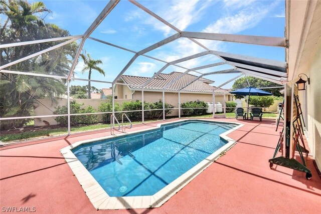 view of pool featuring glass enclosure and a patio area