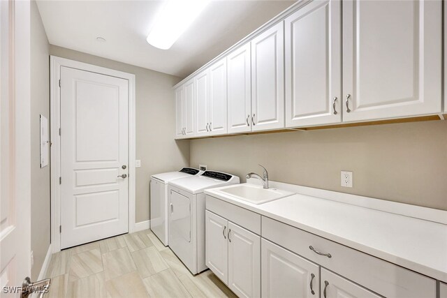 laundry room with cabinets, independent washer and dryer, and sink