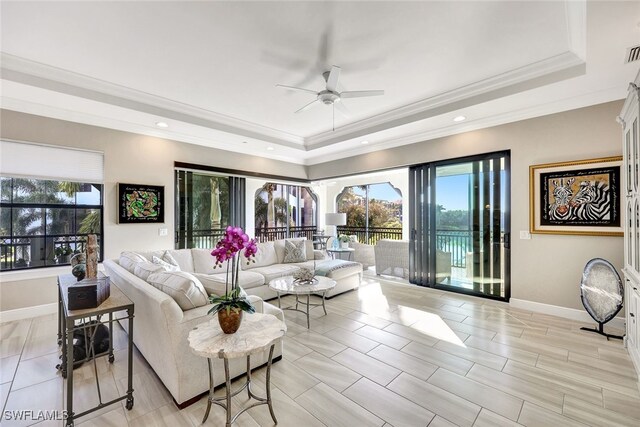 living room with light hardwood / wood-style floors, a raised ceiling, ceiling fan, and ornamental molding