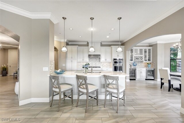 kitchen with wine cooler, stainless steel double oven, pendant lighting, and ornamental molding