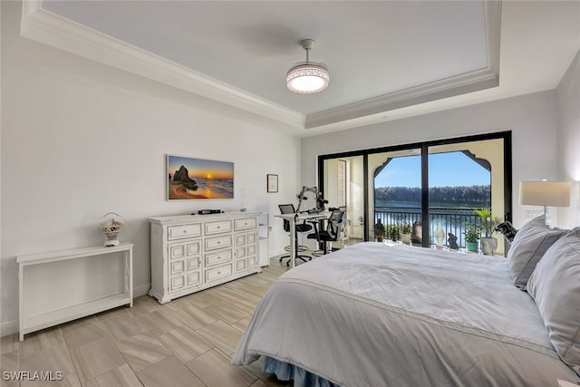 bedroom featuring a raised ceiling, access to exterior, crown molding, and a water view