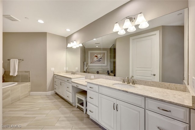 bathroom with a washtub, vanity, and tile patterned flooring