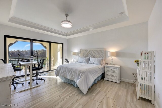 bedroom with light hardwood / wood-style floors, access to outside, and a tray ceiling