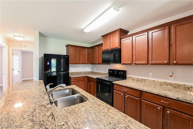 kitchen featuring light stone counters, sink, and black appliances