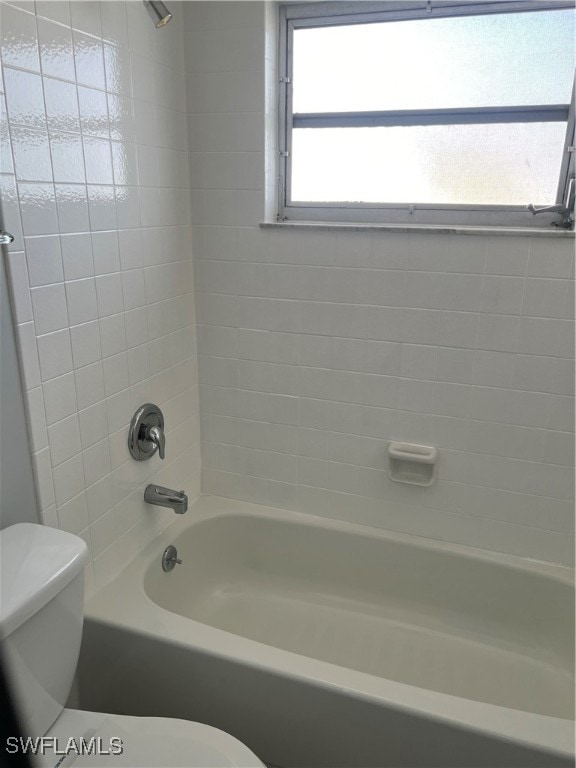 bathroom featuring tiled shower / bath combo and toilet