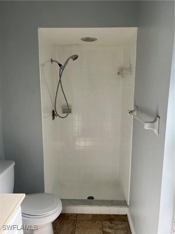 bathroom featuring tile patterned floors, tiled shower, toilet, and vanity