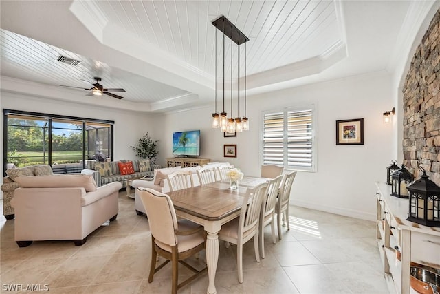 tiled dining area with ceiling fan with notable chandelier, a tray ceiling, crown molding, and a wealth of natural light