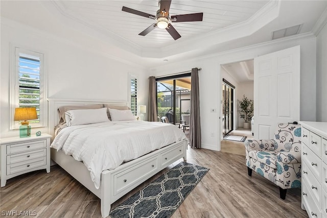 bedroom featuring light hardwood / wood-style floors, crown molding, ceiling fan, a tray ceiling, and access to exterior