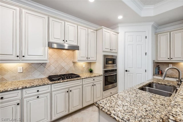 kitchen with decorative backsplash, crown molding, white cabinetry, appliances with stainless steel finishes, and sink