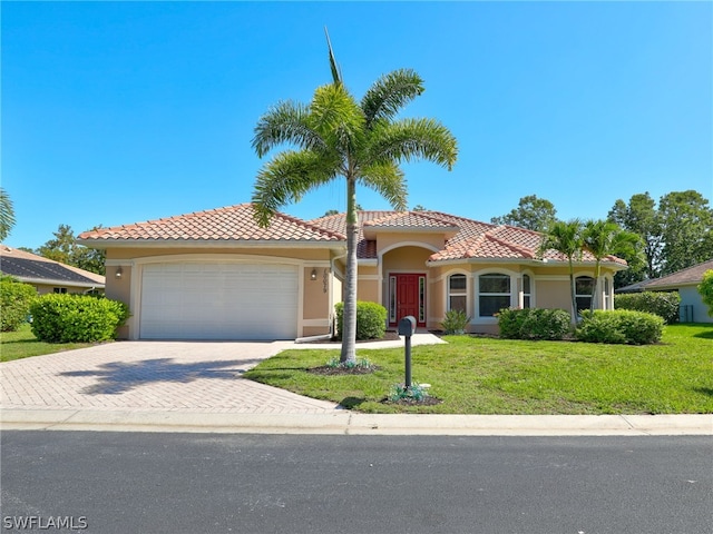 mediterranean / spanish-style home featuring a garage and a front lawn