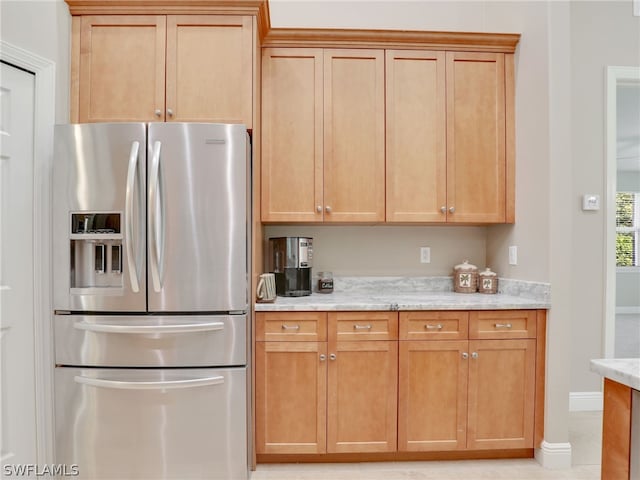 kitchen with light stone countertops and stainless steel refrigerator with ice dispenser