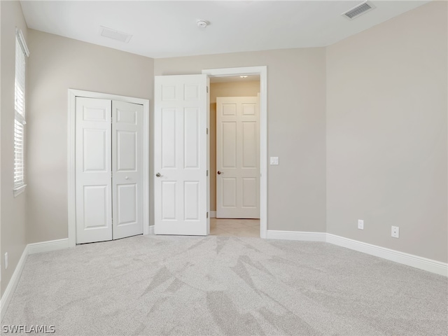 unfurnished bedroom with a closet and light colored carpet