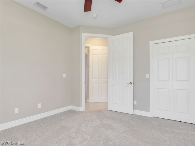 unfurnished bedroom with light colored carpet, a closet, and ceiling fan