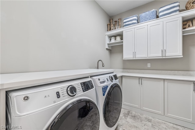 clothes washing area featuring cabinets and washer and dryer