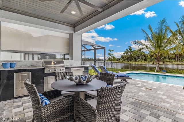 view of patio with a fenced in pool, an outdoor kitchen, a grill, a water view, and ceiling fan